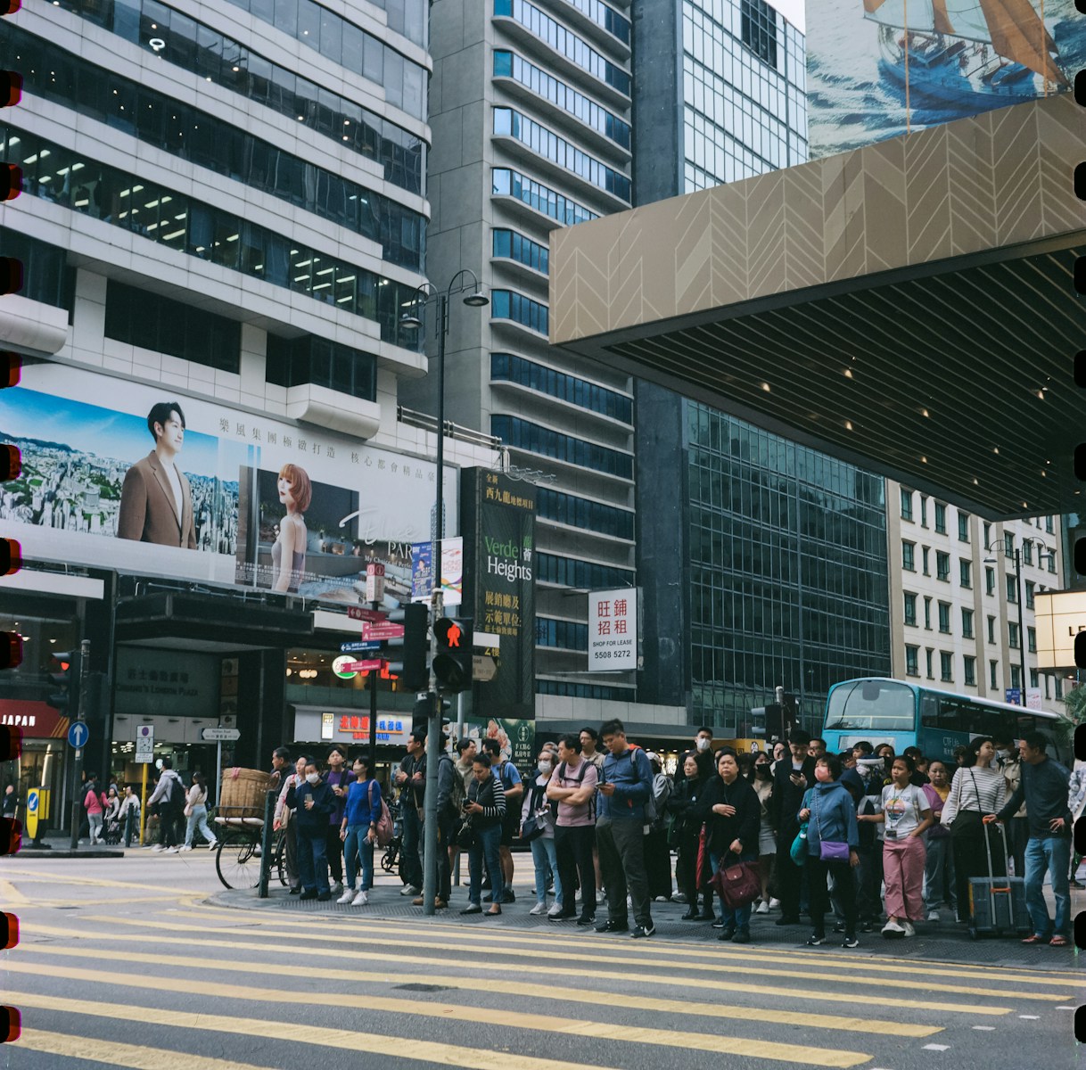 People wait at a crosswalk in a city.